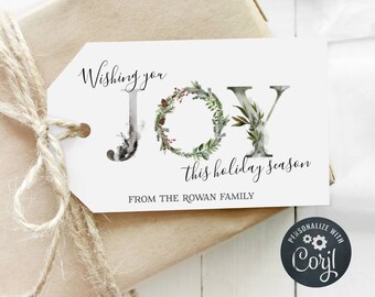 May include: A white gift tag with the words "Wishing you JOY this holiday season" in elegant script. The letter "O" is a wreath. The tag is tied to a wrapped gift with twine.