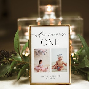 May include: A gold-framed photo with two pictures of babies. The text "when we were one" is at the top of the frame. The text "Maisie & Tanner 07.07.24" is at the bottom of the frame.