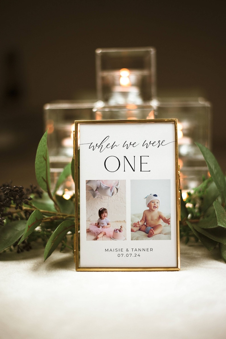 May include: A gold-framed photo with two pictures of babies. The text "when we were one" is at the top of the frame. The text "Maisie & Tanner 07.07.24" is at the bottom of the frame.