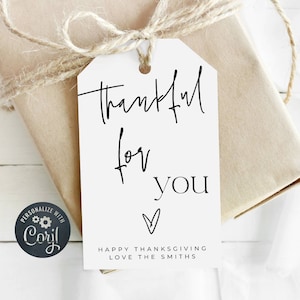 May include: A white gift tag with the words "thankful for you" in black script, tied to a wrapped gift with twine. The tag also includes a heart symbol and the text "Happy Thanksgiving Love The Smiths."