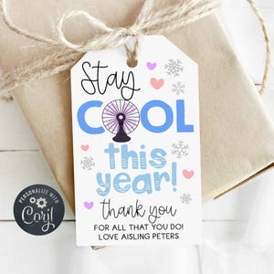 以下が含まれることがあります： 上部が丸みを帯びた白い長方形のギフトタグ。Stay Cool this year! thank you FOR ALL THAT YOU DO! LOVE AISLING PETERSという文字が書かれています。紫色の扇風機のイラスト、小さなピンクと紫のハート、灰色の雪の結晶がデザインされています。