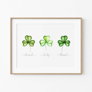 May include: A printable art print with three watercolor shamrocks, each with a different shade of green. The shamrocks are labeled "charmed", "lucky", and "blessed".