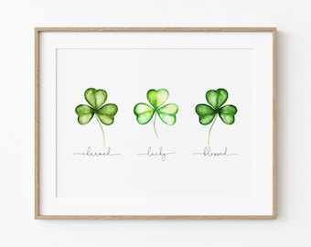 May include: A printable art print with three watercolor shamrocks, each with a different shade of green. The shamrocks are labeled "charmed", "lucky", and "blessed".