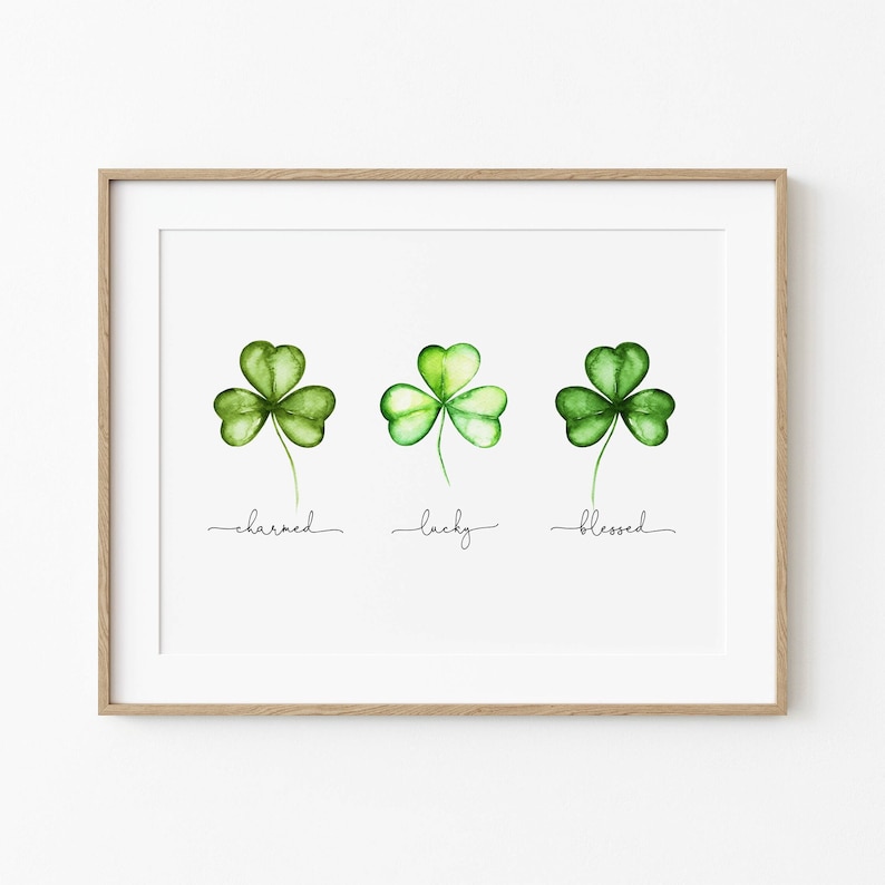 May include: A printable art print with three watercolor shamrocks, each with a different shade of green. The shamrocks are labeled "charmed", "lucky", and "blessed".