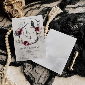 May include: A Halloween party invitation with a watercolor illustration of skulls, roses, and a raven on a branch. The text reads "Please join us for a Halloween Party, Saturday October 31st, from 7pm, McKenzie's Haunted House, 27 Smith St, Portland, RSVP to Sophie 500 000 000, don't be caught dead without a costume."