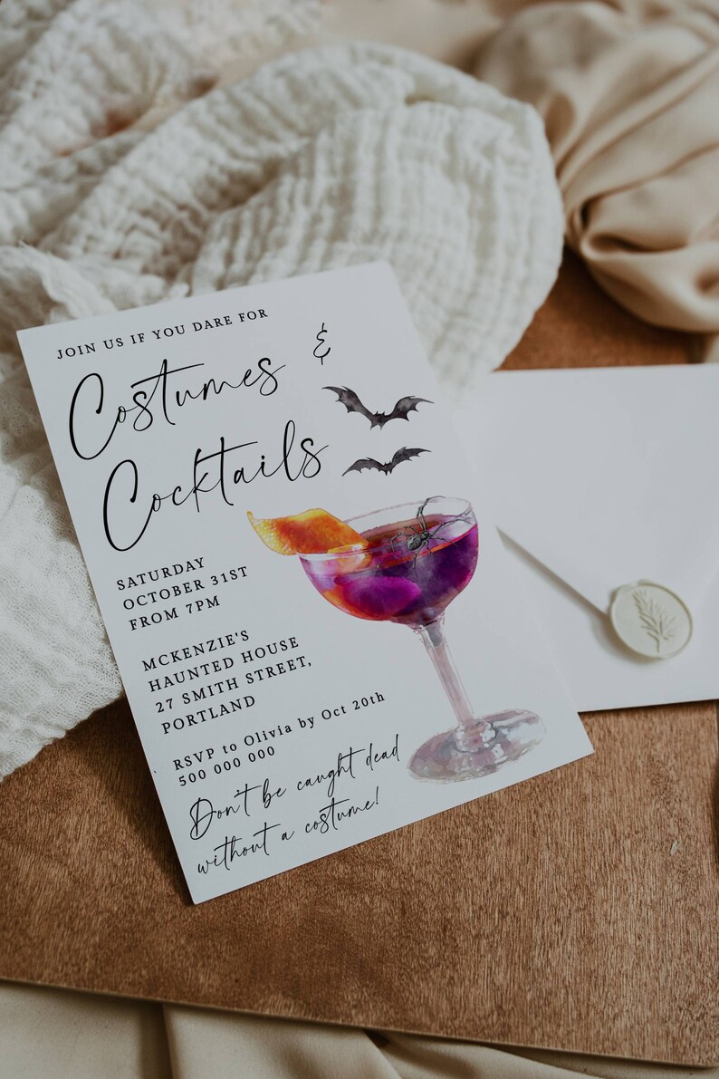 K&ouml;nnte beinhalten: Eine wei&szlig;e Einladungskarte mit schwarzem Text, der "Join us if you dare for Costumes & Cocktails" lautet. Die Karte zeigt eine Aquarell-Illustration eines Cocktailglases mit einem violetten Getr&auml;nk, einer Orangenscheibe und einer Spinne. Der Text enth&auml;lt auch das Datum, die Uhrzeit und den Ort der Veranstaltung. Der Text "Don't be caught dead without a costume!" ist in Kursivschrift geschrieben.