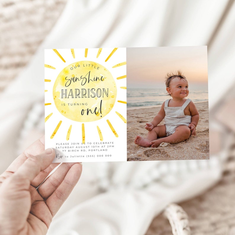 May include: A rectangular birthday invitation card featuring a yellow watercolor sun illustration with the text OUR LITTLE sunshine HARRISON IS TURNING one! and event details. The right side displays a photograph of a toddler sitting on a beach.