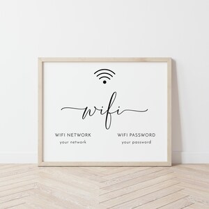 May include: A framed white sign with the word "wifi" in a cursive font, a wifi symbol, and prompts for "WIFI NETWORK" and "WIFI PASSWORD". The frame is a light wood color.