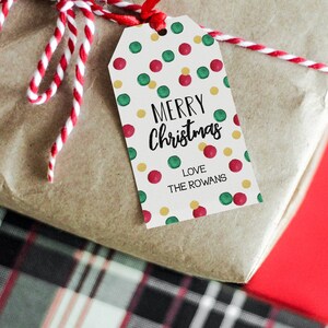 May include: A white gift tag with a red and green polka dot pattern. The tag says "Merry Christmas" in black script and "Love The Rowans" in black text.