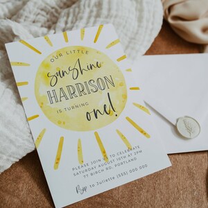 May include: A yellow and white birthday invitation with a sun illustration and the text "Our Little Sunshine Harrison is turning one!"  Please join us to celebrate Saturday August 10th at 2pm 77 Birch Rd, Portland RSVP to Juliette (555) 000 0000