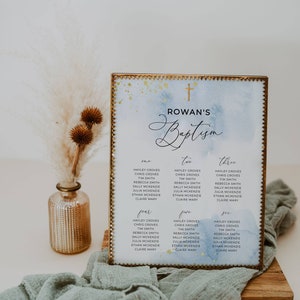 May include: A baptism seating chart with a gold frame, featuring a watercolor wash of blue and gold accents. The chart displays names organized by table number, with the text "Rowan's Baptism" at the top.
