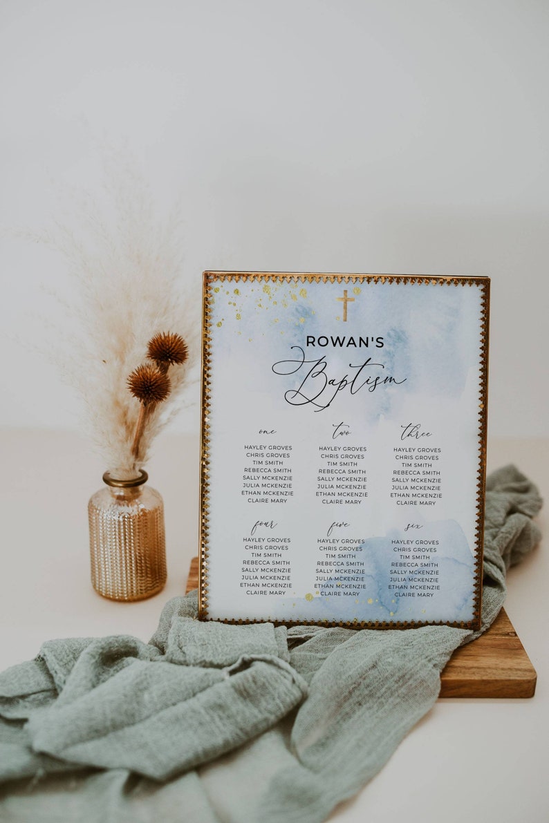 May include: A baptism seating chart with a gold frame, featuring a watercolor wash of blue and gold accents. The chart displays names organized by table number, with the text "Rowan's Baptism" at the top.