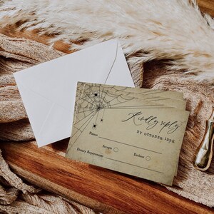 Puede incluir: Una tarjeta RSVP de estilo vintage con un dise&ntilde;o de telara&ntilde;a y el texto "Kindly reply by October 12th". La tarjeta tiene espacio para nombres, requisitos diet&eacute;ticos y una opci&oacute;n para aceptar o rechazar.