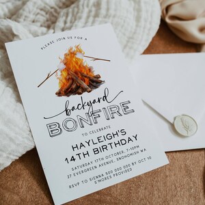 May include: White invitation card with black text announcing a backyard bonfire to celebrate a 14th birthday. The card features a watercolor illustration of a campfire with marshmallows on sticks.