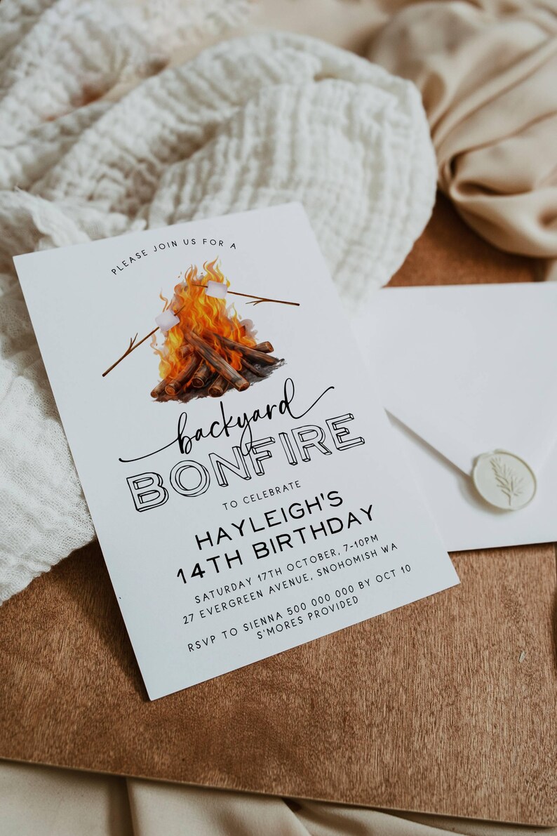 May include: White invitation card with black text announcing a backyard bonfire to celebrate a 14th birthday. The card features a watercolor illustration of a campfire with marshmallows on sticks.