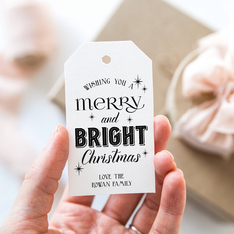 May include: White gift tag with black text that reads "Wishing you a merry and bright Christmas."  The text is in a festive font with stars.  The tag also includes the text "Love the Rowan Family."