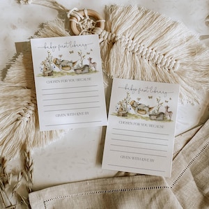 Pu&ograve; includere: Due carte bianche con un'illustrazione di animali del bosco e il testo "baby's first library". Le carte hanno righe per scrivere "scelto per te perch&eacute;" e "dato con amore da".