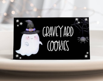 Puede incluir: Señal imprimible en blanco y negro con un lindo fantasma con un sombrero de bruja y el texto "Graveyard Cookies". La señal tiene una telaraña y una araña en la esquina superior derecha.