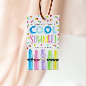 May include: A gift tag with a brown leather string. The tag has the text "WISHING YOU A COOL SUMMER! LOVE SIENNA" in colorful letters. Below the text are five cartoon characters wearing sunglasses.