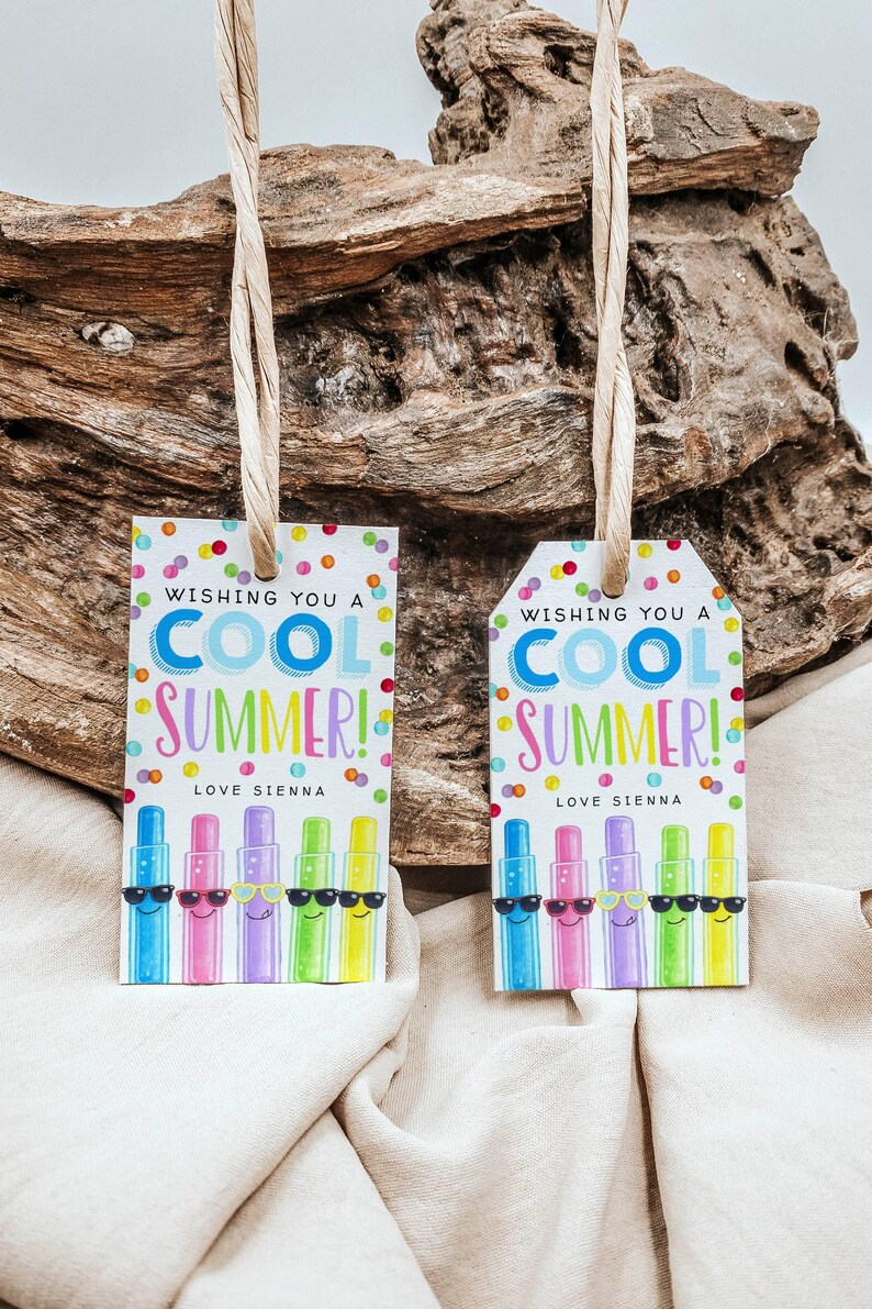 May include: Two gift tags with the text "Wishing you a COOL SUMMER!" and "Love Sienna." The tags feature colorful cartoon-style illustrations of sunscreen bottles wearing sunglasses. The tags are hanging from a natural fiber string.