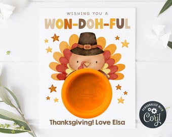 Puede incluir: Una tarjeta de Acción de Gracias con un pavo de dibujos animados que lleva un sombrero de peregrino y sostiene un recipiente de plastilina. La tarjeta dice "Wishing you a Won-Doh-Ful Thanksgiving! Love Elsa".