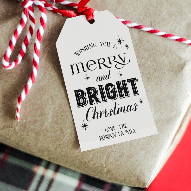 May include: White gift tag with black text that reads "Wishing you a merry and bright Christmas" with stars and a message at the bottom that reads "Love the Rowan Family".
