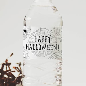 May include: A clear water bottle with a white label featuring a black spiderweb design and the words "HAPPY HALLOWEEN!" in a spooky font. A small black spider is visible on the upper left of the label. The bottle is filled with clear liquid.
