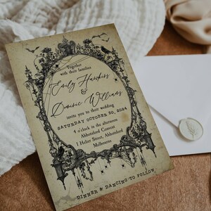 Puede incluir: Una invitaci&oacute;n de boda de estilo vintage con una ilustraci&oacute;n en blanco y negro de un arco g&oacute;tico con murci&eacute;lagos, ara&ntilde;as y un cuervo. El texto dice "Juntos con sus familias Emily Hamper & Dominic Williams les invitan a su boda S&aacute;bado 30 de octubre de 2024 4 en punto de la tarde Abbotsford Convent 1 Helier Street, Abbotsford Melbourne Cena y baile a continuaci&oacute;n"