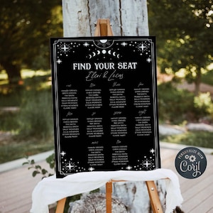 May include: A black rectangular wedding seating chart sign with white text reading Find Your Seat, Eleni & Lucas, and a list of names under tables one through ten. The design features white celestial motifs including stars and moon phases.