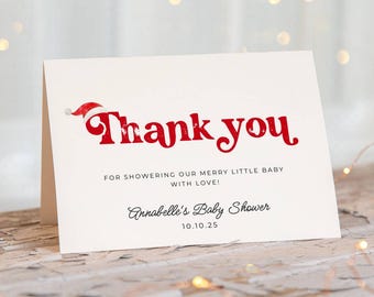 Könnte beinhalten: Eine weiße, gefaltete Dankeskarte mit dem roten Schriftzug Thank you und einer kleinen rot-weißen Weihnachtsmütze auf dem Buchstaben T. Darunter steht FOR SHOWERING OUR MERRY LITTLE BABY WITH LOVE! Annabelle's Baby Shower und das Datum 10.10.25.