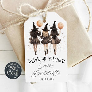 May include: A white gift tag with three witches wearing black dresses and pointy hats. They are holding orange balloons and walking towards the right. The text on the tag reads "Drink up witches! Quinn's Bachelorette 10.26.24"