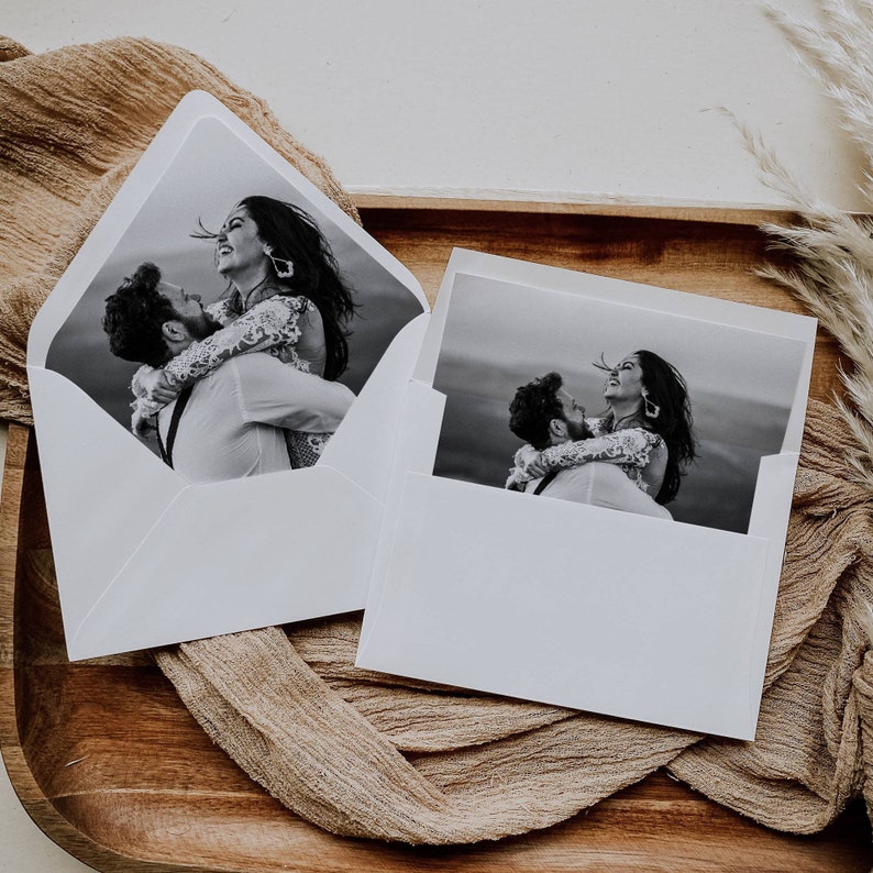 May include: Two white envelopes with black and white photographs of a couple embracing. The couple is dressed in formal attire and the photos are set against a blurred background.