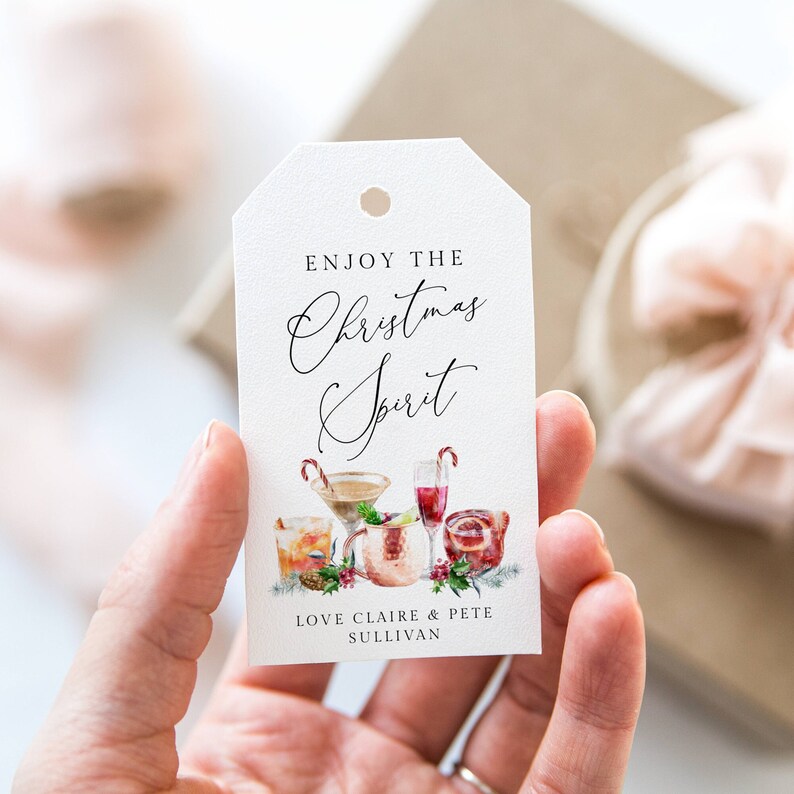 May include: White gift tag with the text "Enjoy the Christmas Spirit" in black cursive font. The tag features a watercolor illustration of holiday cocktails and the text "Love Claire & Pete Sullivan".