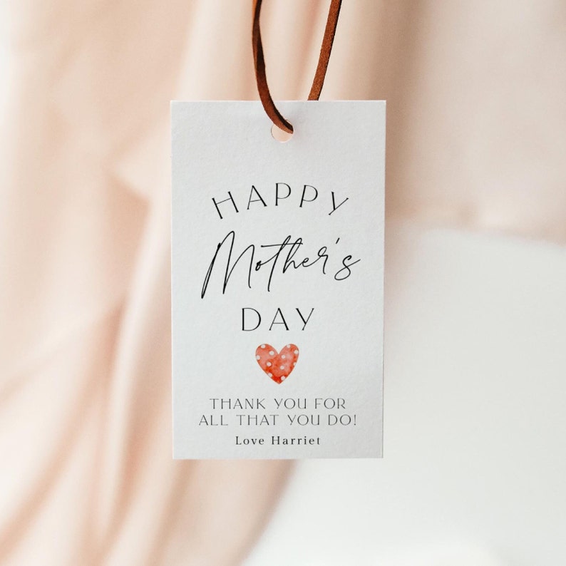 Pu&ograve; includere: Etichetta regalo bianca con il testo "Buon giorno della mamma" e un cuore rosso con pois bianchi. Il testo sotto il cuore dice "Grazie per tutto quello che fai! Con affetto, Harriet."