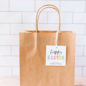May include: A brown paper gift bag with a white gift tag that says "Happy Easter" in colorful letters and "With Love Annabelle Simons".