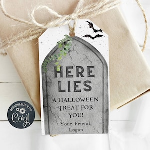 May include: A white gift tag with a gray tombstone illustration. The tombstone has the text "HERE LIES" and "A HALLOWEEN TREAT FOR YOU!" with the text "Your Friend, Logan" at the bottom. The tag has a white background with a black bat and stars.