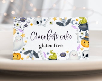 May include: A white card with a Halloween theme featuring ghosts, bats, spiders, pumpkins, and candy. The text on the card reads "Chocolate cake gluten free".