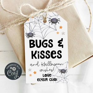 Puede incluir: Una etiqueta de regalo blanca con un diseño de telaraña y arañas negras. El texto dice "Bugs & Kisses and Halloween wishes! Love Elysia Choi".