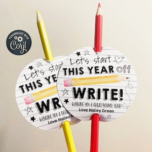 May include: Two pencils with attached circular tags. The tags have a black and white school-themed design with the text "Let's start this year off write!" and "Wishing you a great school year! Love Hailey Green".