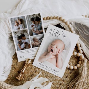 May include: Two white baby announcement cards with photos and text. One card has a collage of family photos. The other card has a baby photo with the word "Hello" and baby's details. A gold wax seal and wooden beads are also in the image.