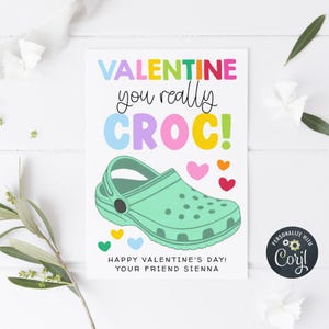 May include: A Valentine's Day card with the words "VALENTINE you really CROC!" in colorful letters. A green clog shoe is featured, along with colorful hearts. The card also says "HAPPY VALENTINE'S DAY! YOUR FRIEND SIENNA."