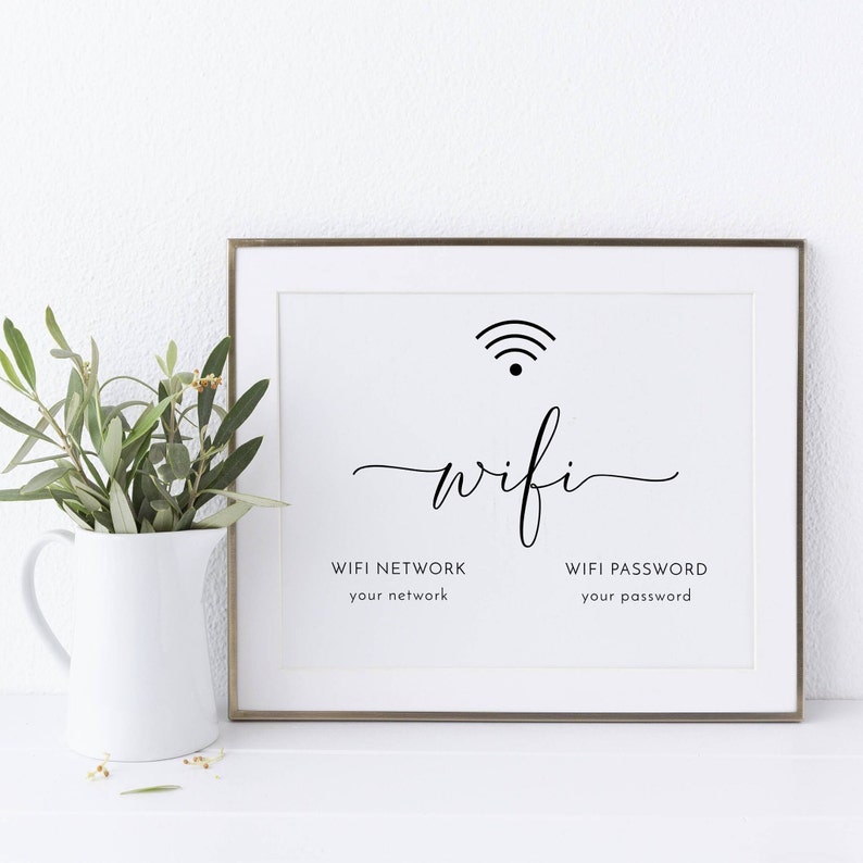 May include: A framed white print with the word "wifi" in elegant script, accompanied by a wifi signal icon. Below, it reads "WIFI NETWORK your network" and "WIFI PASSWORD your password". A white pitcher with greenery sits to the left.