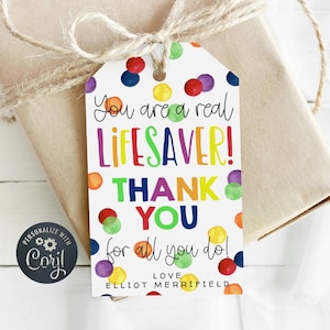 Op de afbeelding: Een wit cadeau-etiket met kleurrijke stippen en de tekst "You are a real LIFESAVER! THANK YOU for all you do! LOVE ELLIOT MERRIFIELD".