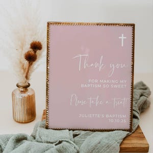 Peut inclure: Une pancarte rose avec un cadre dor&eacute; et une croix blanche en haut. La pancarte indique "Merci d'avoir rendu mon bapt&ecirc;me si doux. Prenez un petit quelque chose !" et "Bapt&ecirc;me de Juliette 10.10.25".