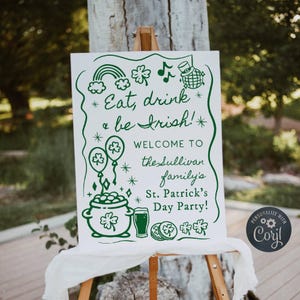 May include: A white sign on a wooden easel with green text and illustrations for a St. Patrick's Day party. The sign reads "Eat, drink & be Irish!" and welcomes guests to the Sullivan family's party. Includes a rainbow, shamrocks, and a pot of gold.