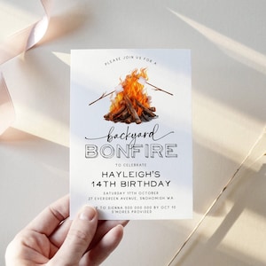 May include: A white invitation with black text for a backyard bonfire party to celebrate a 14th birthday. The invitation features a watercolor illustration of a campfire with marshmallows on sticks. The text reads "Please join us for a backyard bonfire to celebrate Hayleigh's 14th birthday. Saturday 17th October, 27 Evergreen Avenue, Snohomish WA. RSVP to Sienna 500 000 000 by Oct 10. S'mores provided."