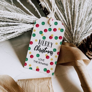 May include: A white gift tag with a red, green, and yellow polka dot pattern. The tag says "Merry Christmas" in black cursive lettering and "Love The Rowans" in black lettering.