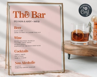 May include: A gold framed sign with a pink background and the text "The Bar" in orange. The sign lists drinks for a wedding reception, including beer, wine, cocktails, and non-alcoholic options.