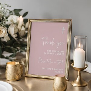 Peut inclure: Un panneau encadr&eacute; en or avec un fond rose et du texte blanc. Le panneau indique "Merci d'avoir rendu mon bapt&ecirc;me si doux. Prenez un petit cadeau ! Bapt&ecirc;me de Juliette 10.10.25".
