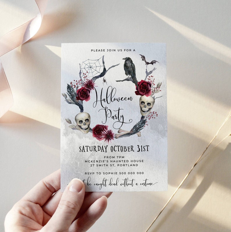 May include: A Halloween party invitation with a watercolor illustration of a skull wreath with red roses, bones, and a raven. The text reads "Please join us for a Halloween Party, Saturday October 31st, From 7pm, McKenzie's Haunted House, 27 Smith St, Portland, RSVP to Sophie 500 000 000, Don't be caught dead without a costume."